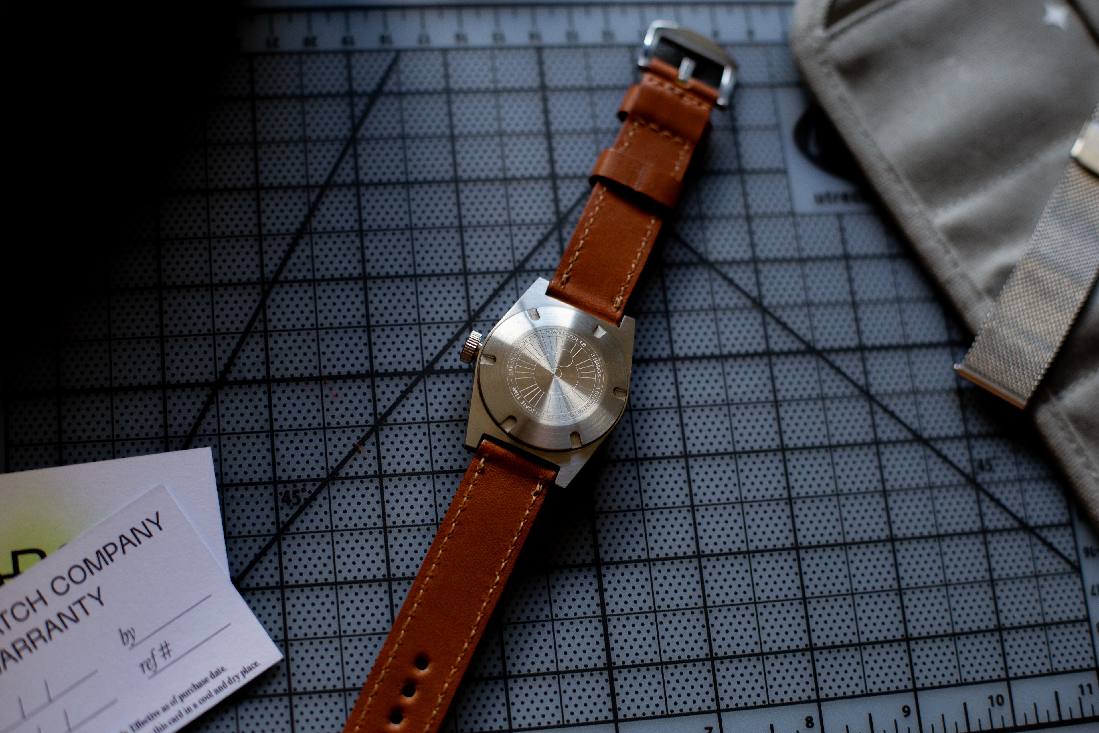 Watch with brown leather strap on a grid surface